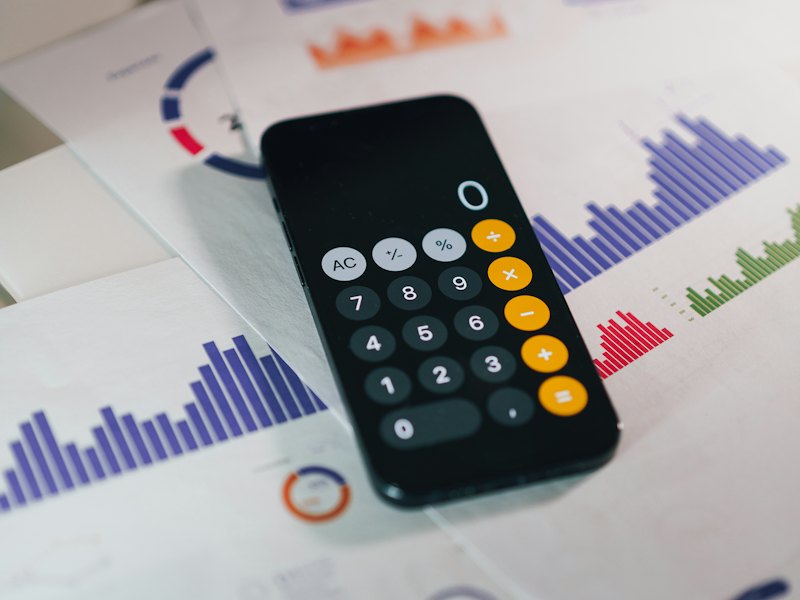 Gider grafiklerinin üzerinde hesap makinesi açık bir akıllı telefon